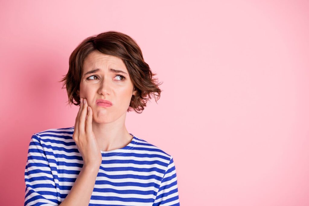 A woman holding her jaw in pain.